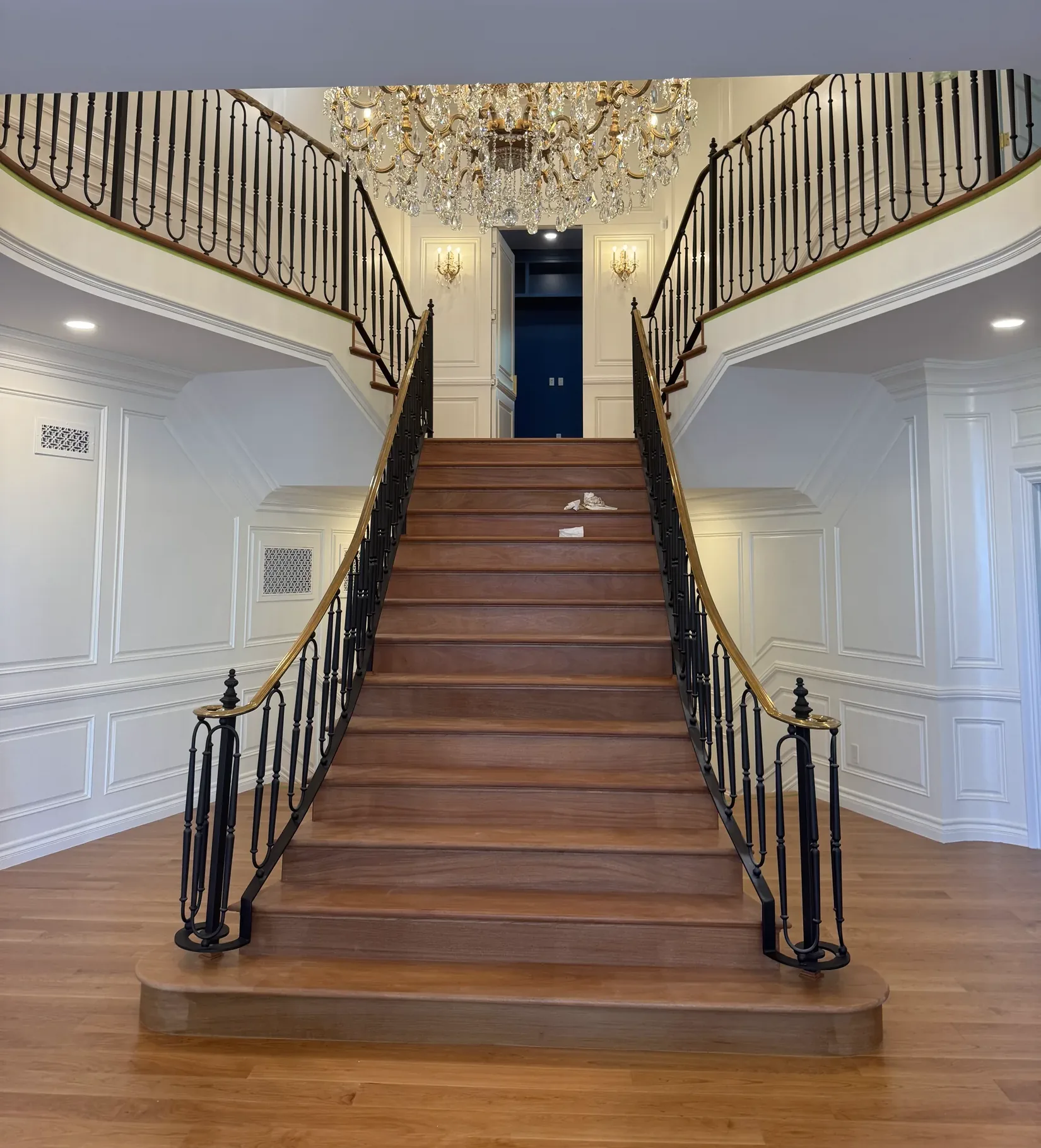 A grand double hardwood staircase with wrought-iron balusters built by SHS Hardwood Flooring